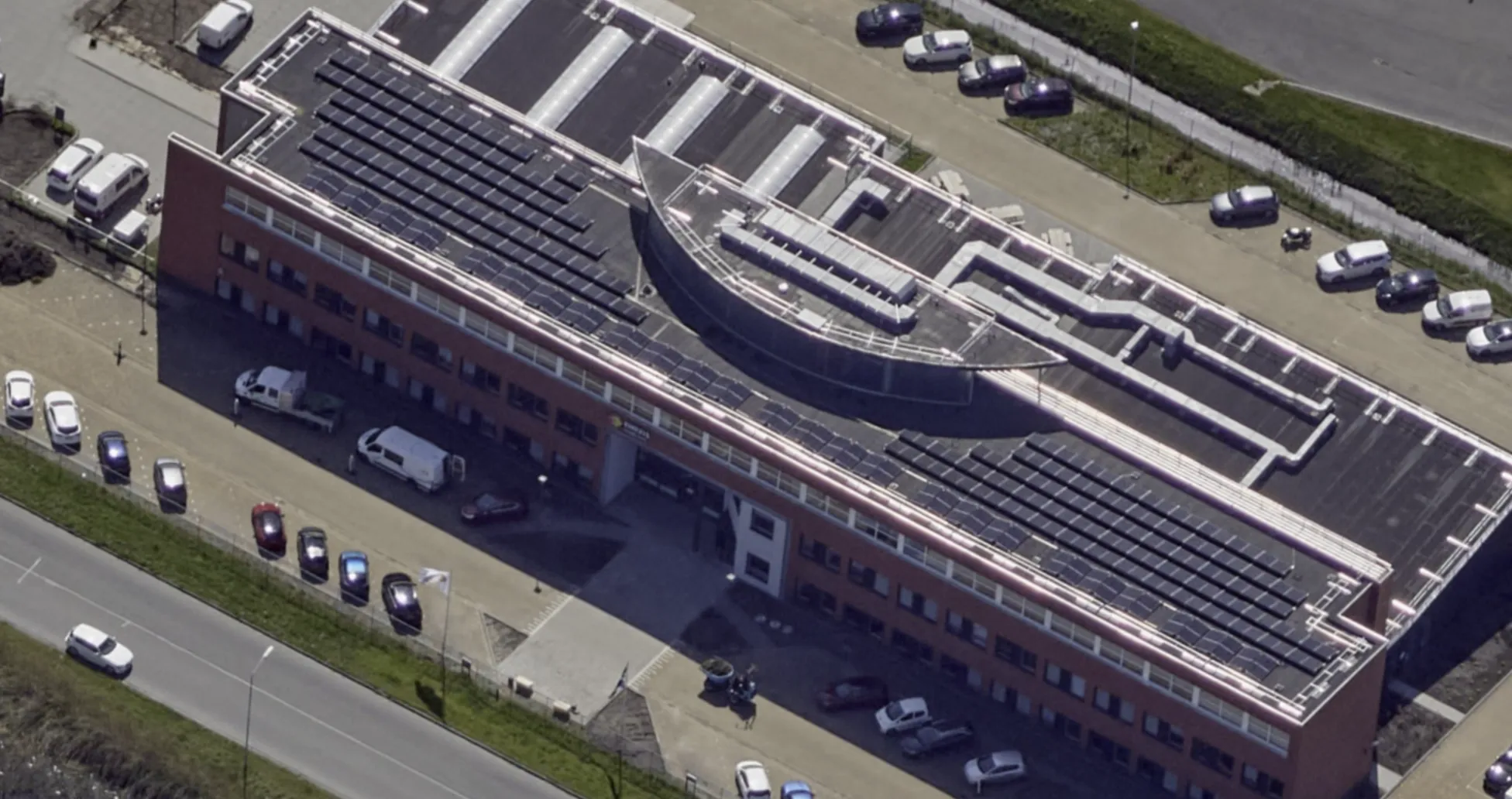 Aerial view of the same Enexis building after installation: solar panels on the roof and a continuous Protector Guardrail roof-edge protection system running around the full perimeter.