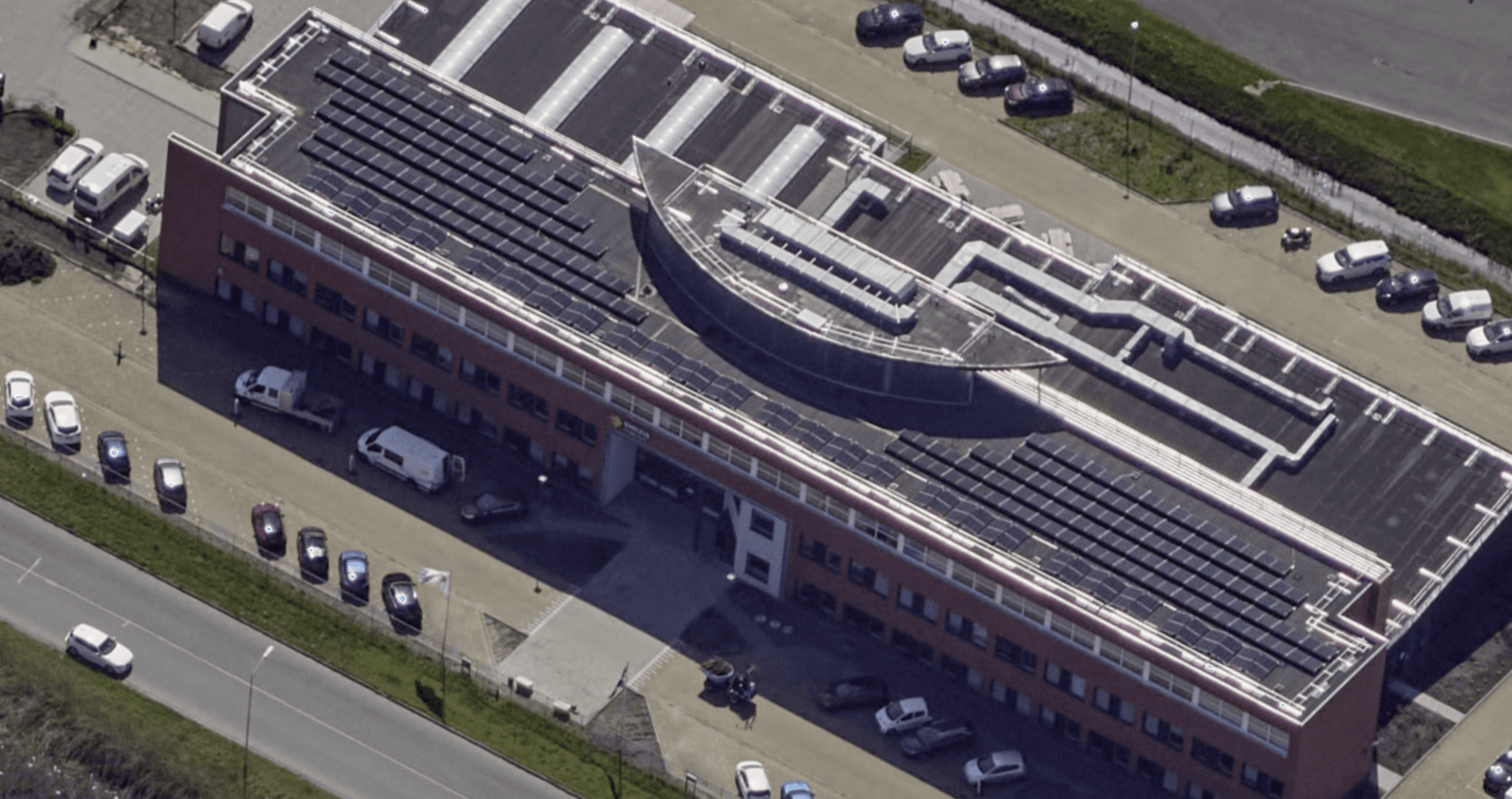 Aerial view of the same Enexis building after installation: solar panels on the roof and a continuous Protector Guardrail roof-edge protection system running around the full perimeter.