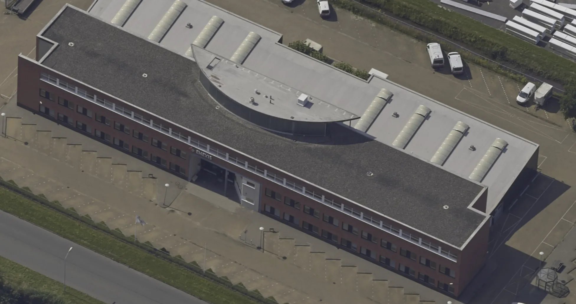 Aerial view of the Enexis building in Kolham before installation: brick office building with an unprotected, bare roof edge.