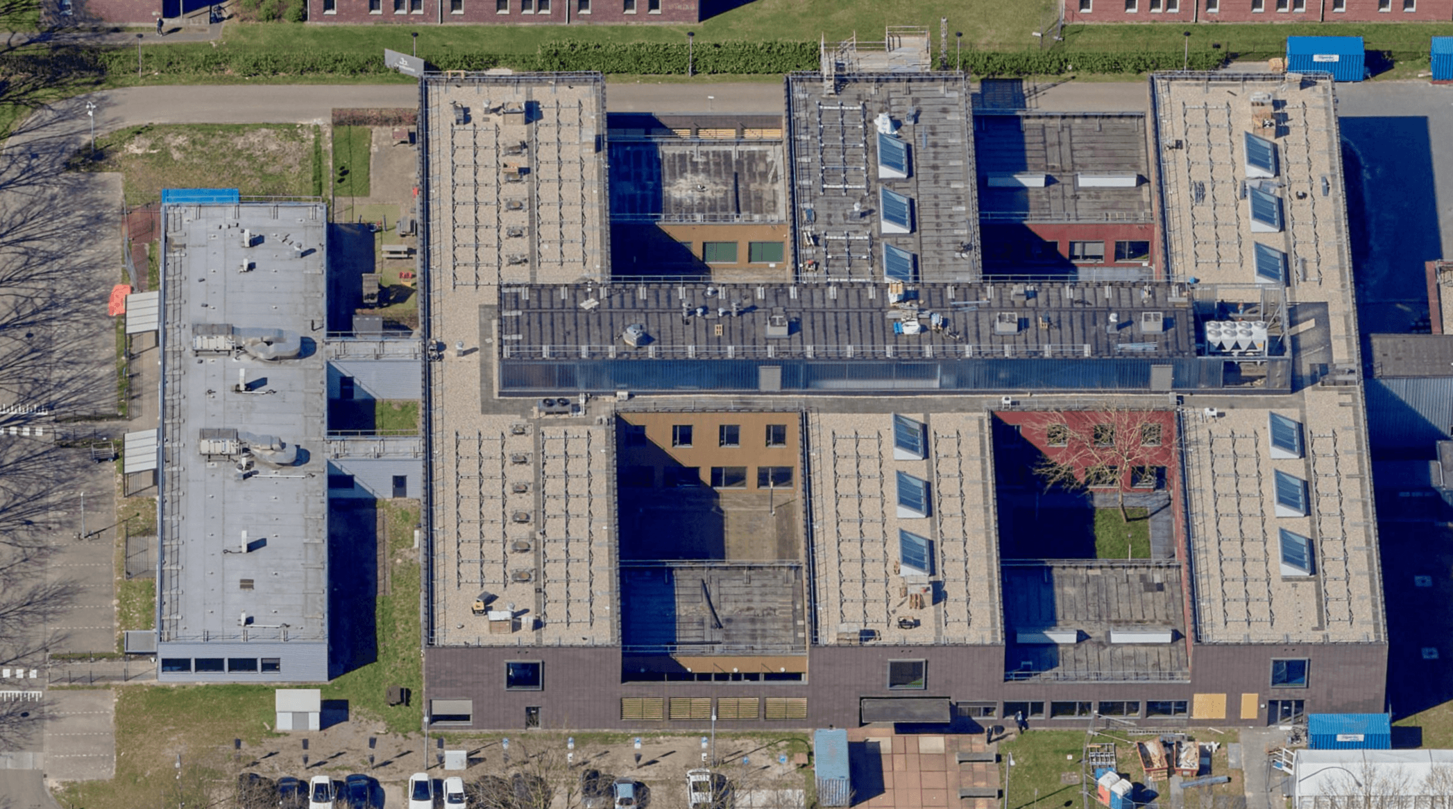 Top-down aerial view of the IND complex in Ter Apel, showing the flat roofs and courtyards of the buildings with Protector Guardrail roof-edge protection along the roof perimeters.