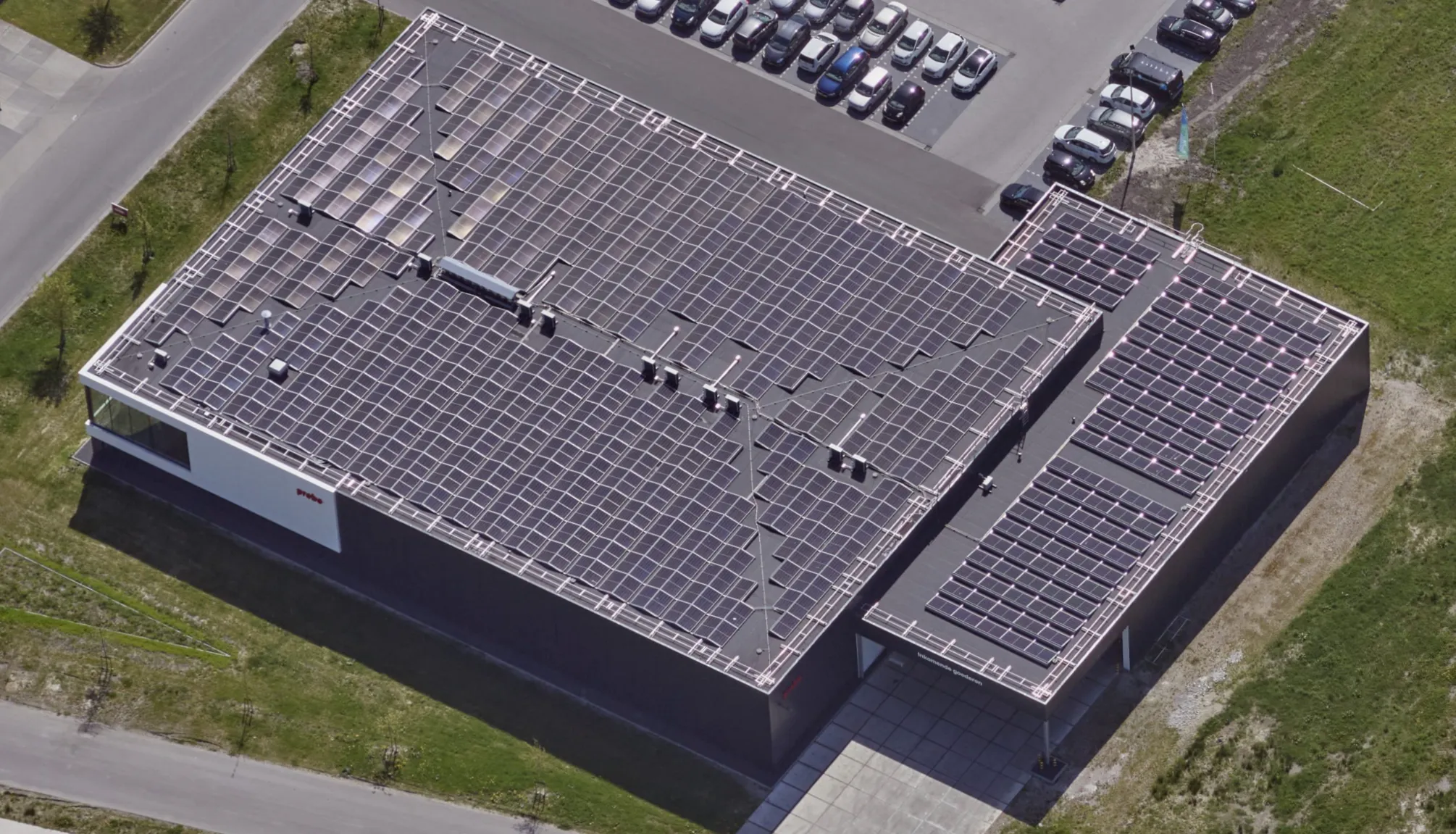 Oblique aerial view of the Probo production building with solar panels on the roof and Protector Guardrail roof-edge protection along the edge.