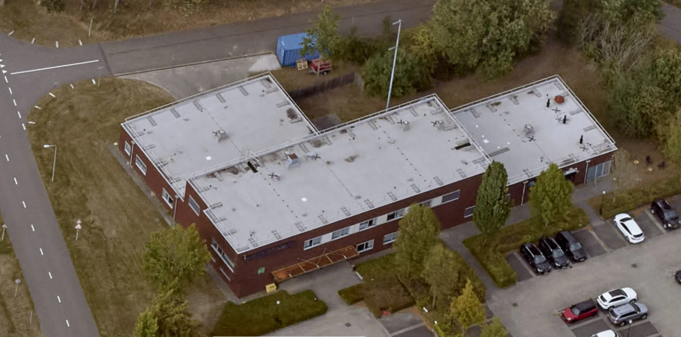 Aerial view of the L-shaped building at Vliegbasis Eindhoven with Protector Guardrail roof-edge protection along the flat roof perimeter.